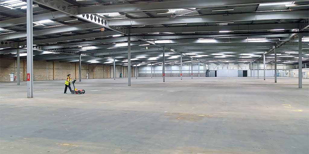 GPR survey of a large warehouse concrete floor slab. The wartehouse is empty with just the surveyor pushing the GPR survey cart.