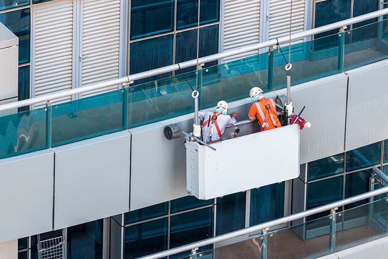 Two inspectors in an access cradle conducting a Building Fire Safety audit inspection
