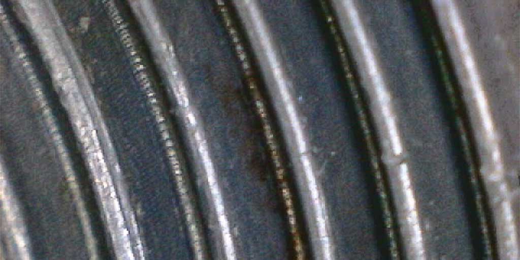 A macro photograph of a contaminated thread on a failed plastic coupling